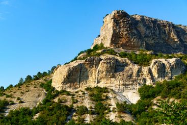 Impressive rocky mountain with lush greenery under a...