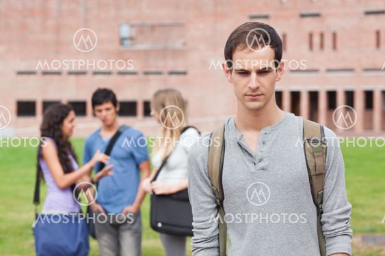 Lonely student posing while his classmates are talking