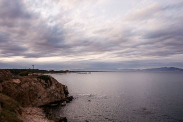 rocky shoreline with a cloudy sky and a calm ocean