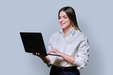 Young woman using laptop on grey studio background