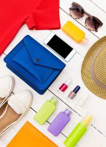 Summer travel essentials arranged on a white wooden...