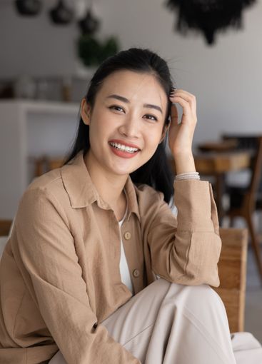 Positive beautiful young Vietnamese woman touching hair