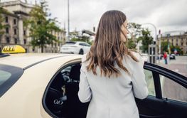 business woman wearing a suit entering taxi