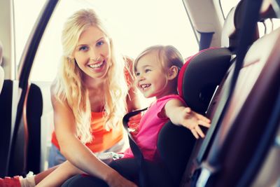 happy mother fastening child with car seat belt