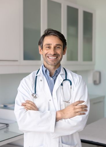 Positive Hispanic male doctor standing with hands folded