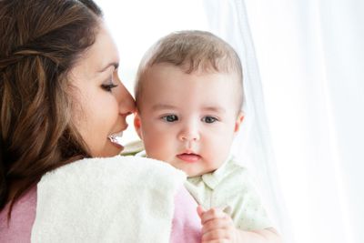Cheerful young mother taking care of her adorable baby