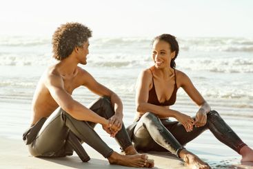 Surfing, sport and friends sitting on the beach together...
