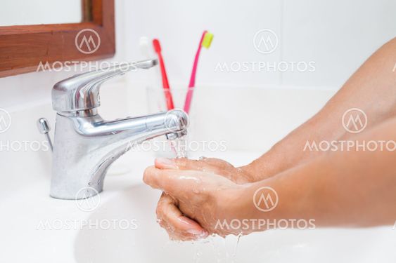 Washing hands under running water in a bathroom (shallow DOF; color toned image)