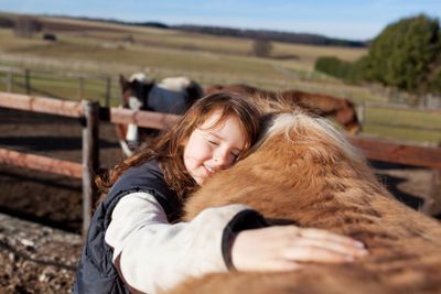 Young girl petting her horse
