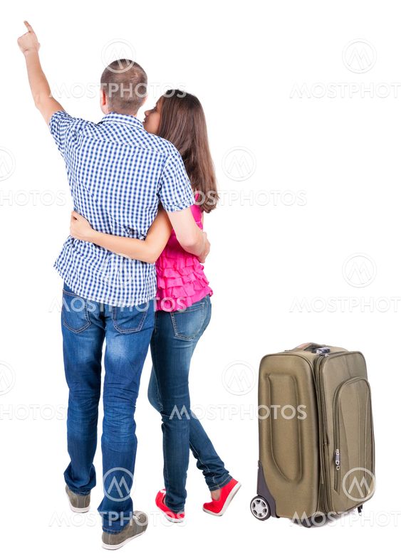 young couple traveling with suitcas and pointing at wal...