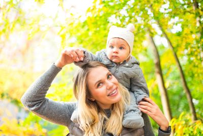 Mother and her little daughter play cuddling on autumn...