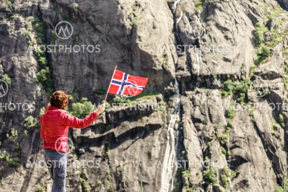 Tourist woman with norwegian flag in rocks mountains