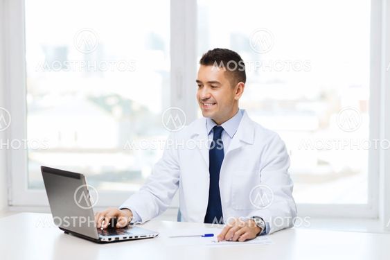 smiling male doctor with laptop in medical office