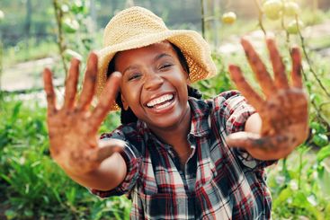 Portrait, dirty hands and black woman in garden, smile...