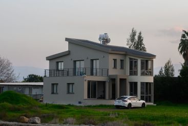 Modern coastal house at dusk with lush surroundings and...