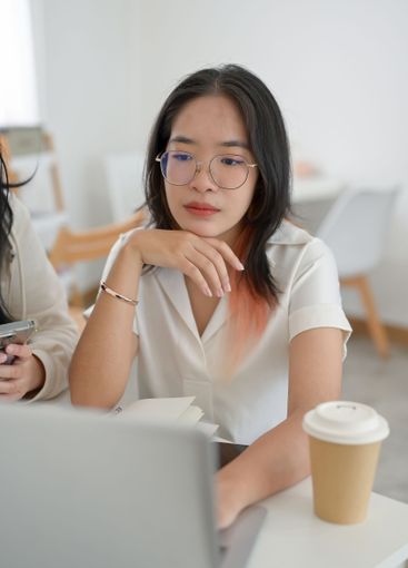 A young, serious Asian woman is concentrating on her...