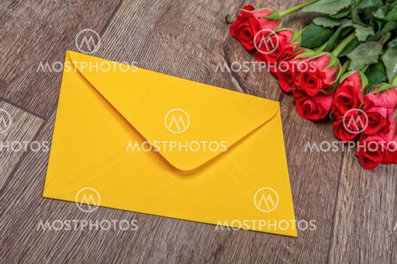 Yellow envelope and roses on a wooden background