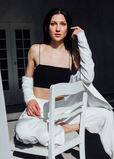 Beautiful slim brunette woman in jacket sitting on chair