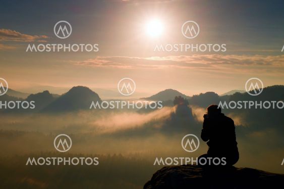 Photograph takes photos of daybreak above heavy misty...