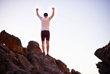 Celebration, rock climber and man on mountain, back and...