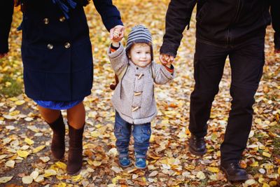 Cute smiling little boy walking with parents 