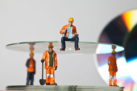 Miniature people in action with CDs