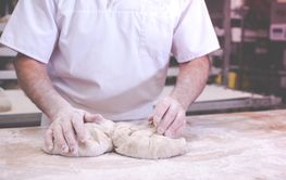 close-up on hands of baker kneading dough to bake fresh...
