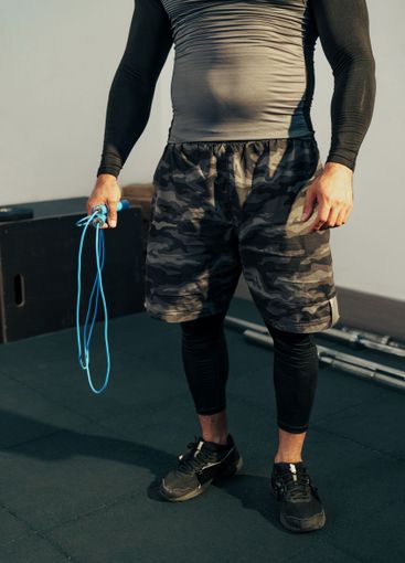 Muscular individual prepares to jump rope in a fitness...