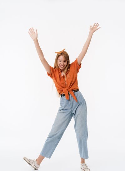 Full length portrait of cheerful young woman wearing...