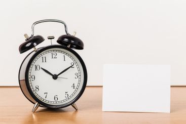 Black vintage alarm clock on wooden table