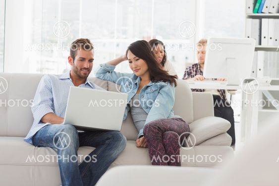 Young smiling designers working on laptop on the couch