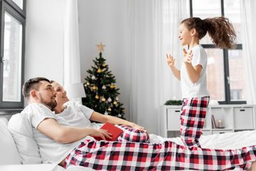 happy girl jumping on parent's bed on christmas