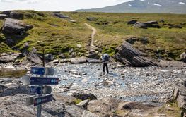 Man hiking through stream by mountain