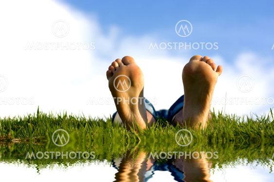 Feets on grass near water.