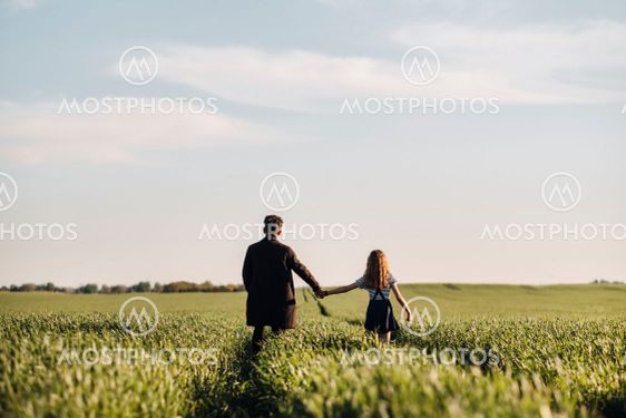 teenage daughter walks with her father in a meadow...