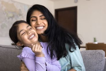 Loving mother cuddling tightly her cute little 5s daughter