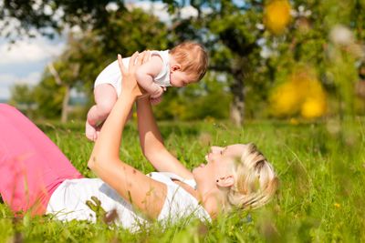Mother playing with baby on meadow