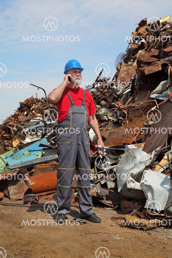 Recycling industry, worker using phone and heap of old metal