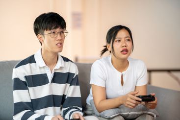 Two young Asian friends are playing a video game...