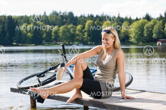 Sport biking young woman sitting by lake
