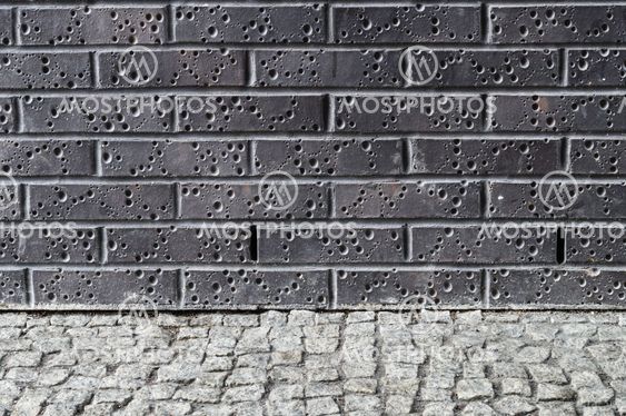 Modern dark brick wall with grey pavement ground
