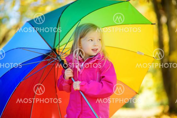 Cute little girl holding rainbow umbrella on beautiful...