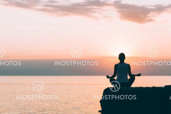 Young woman doing yoga by the sea