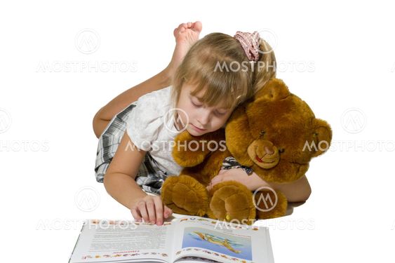 Beautiful little girl playing with a bear. She smiles and looks at the big plush teddy bear.
