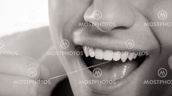Young man cleaning her white teeth with dental floss
