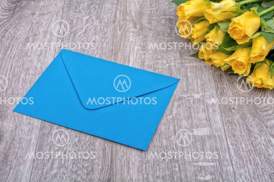 Blue envelope and roses on a wooden background