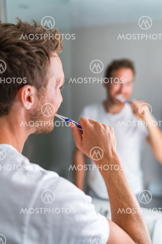 Man brushing teeth in the morning looking in bathroom...