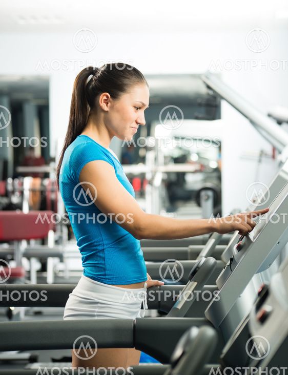 attractive young woman adjusts the treadmill
