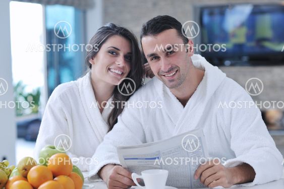 Happy couple reading the newspaper in the kitchen at breakfast