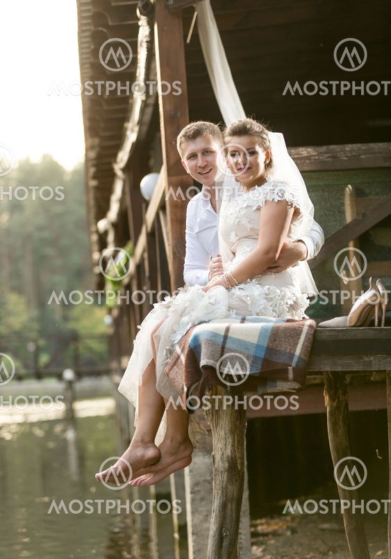 newly married couple sitting next to river at forest